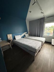 a bedroom with two beds and a window at Ibis Budget Lyon Caluire Cité Internationale in Caluire-et-Cuire +31 photos