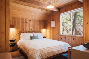 Pine CoveにあるThe Dusk House - An Idyllwild A-Frameの木製の壁とベッドのある寝室