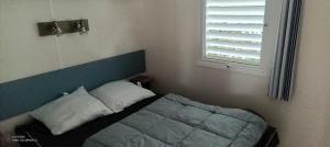 a bedroom with a bed with a blue headboard and a window at Mobilhome Oléron in Les Sables Vignier +8 photos