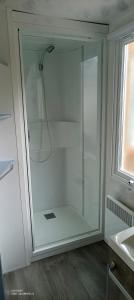 a glass shower in a bathroom next to a sink at Mobilhome Oléron in Les Sables Vignier