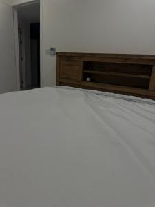 a bedroom with a white bed with a wooden dresser at Sea and lake view apartment in Muscat
