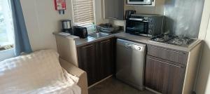 Una pequeña cocina con estufa y microondas. en Mobilhome - La Palmyre Camping, en La Palmyre