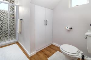 een witte badkamer met toilet en douche bij Hideaway Self-Catering Studio in Melkbosstrand