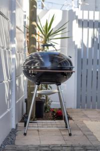 a bbq grill on a stand on a patio at Hideaway Self-Catering Studio in Melkbosstrand +17 photos