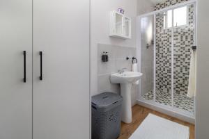 a white bathroom with a sink and a shower at Hideaway Self-Catering Studio in Melkbosstrand