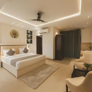 Un dormitorio con una cama grande y dos sillas. en The Ginger, Vrindavan #Big Swimming Pool #luxury Rooms # Lush Garden # Family Friendly # Kids Play Zone # Calm & Spiritual Vibes # Away From City Hustle# By elegance group#, en Vrindāvan