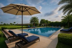 una piscina con sillas y una sombrilla junto a una piscina en The Ginger, Vrindavan #Big Swimming Pool #luxury Rooms # Lush Garden # Family Friendly # Kids Play Zone # Calm & Spiritual Vibes # Away From City Hustle# By elegance group#, en Vrindāvan 38 fotos más