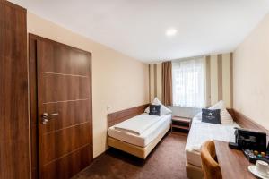 a hotel room with two beds and a door at Aspire Castillo Reutlingen, Trademark Collection by Wyndham in Reutlingen