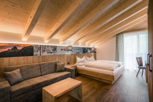 Habitación de hotel con cama y sofá en Hotel Jägerhof, en Colfosco