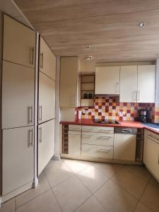 a kitchen with white cabinets and tiles on the wall at T3 Le logis de Martin - city center - near Ducale Place with parking space in Charleville-Mézières