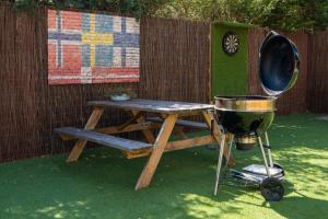 a grill next to a picnic table and a bbq at Drents Genieten - Goudheide met privé jacuzzi & sauna in Erm