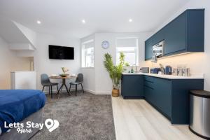a kitchen and dining room with blue cabinets and a table at Eden Bay Serviced Apartments - Eden in Morecambe +8 photos