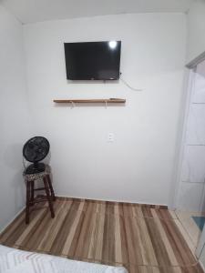 Una habitación con una silla y un televisor en la pared. en SUÍTE NOMAR 1 campos prado, en Brotas