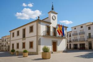 a building with a clock tower with flags on it at La Casita de Rosi in Navaluenga