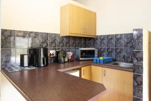 a kitchen with wooden cabinets and a counter top at Stonebreaker Country Lodge in Oudtshoorn