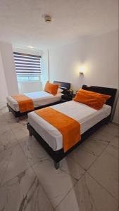 a room with two beds with orange pillows at departamento frete al mar in Manzanillo