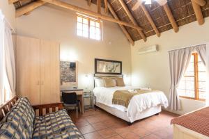 a bedroom with a bed and a desk and a chair at Stonebreaker Country Lodge in Oudtshoorn