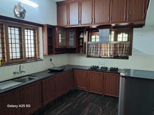eine Küche mit Holzschränken und einer Spüle in der Unterkunft 3 BHK House in Thrissur