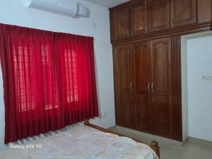 ein Schlafzimmer mit roten Vorhängen und einem Bett und Schränken in der Unterkunft 3 BHK House in Thrissur
