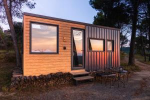 a tiny house with windows and a table and chairs at Cabañas en el bosque cerca de Barcelona in Talamanca