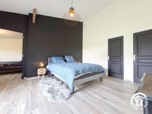 a bedroom with a blue bed and a black wall at Au brunet in Saint-Élix-Theux