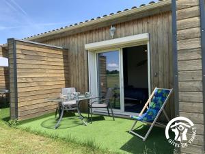 a patio with a table and chairs on the grass at Au brunet in Saint-Élix-Theux