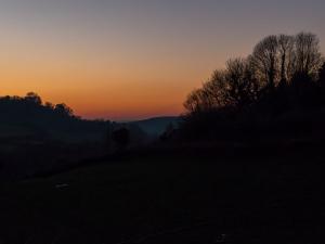 PowerstockにあるThe Three Horseshoesの手前の木々が茂る丘の夕日