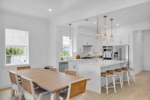 a white kitchen with a wooden table and chairs at New Luxury Home in Private Community - with Pool, Beach & Pickleball Court in Marathon +59 photos