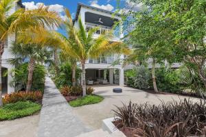 an exterior view of a white house with palm trees at New Luxury Home in Private Community - with Pool, Beach & Pickleball Court in Marathon