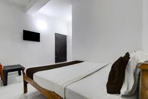 a white bedroom with a bed and a table at Hotel O Shree Guest House in Khandagiri +21 photos
