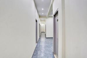 a corridor of an office building with white walls and blue floors at Hotel O Brij Ghat Mukteshwar Formerly Brijwasi Guest House in Kankather