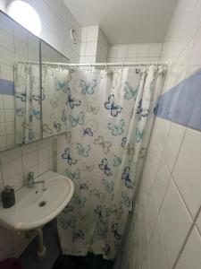 a bathroom with a sink and a shower curtain with butterflies at City Nook in Stockholm