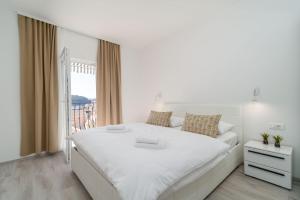 a white bedroom with a large bed and a window at The Loft in Mokošica