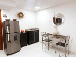 Una cocina con refrigerador de acero inoxidable y una mesa. en Apartamento centro a una cuadra de la playa y parque de los novios, en Santa Marta