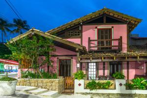 a pink house with a window and a balcony at Villa do Portinho - Casas em frente à Praia in Ilhabela