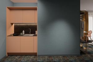 a kitchen with brown cabinets and a blue wall at Hôtel Kempf in Colmar