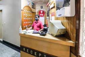 Un hombre con una máscara en un mostrador de una tienda. en Hotel O Surya, en Ludhiana