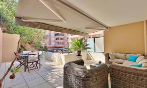 a patio with a couch and chairs and a table at Charmant appart rénové centre plages à 5 minutes in Théoule-sur-Mer