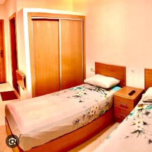 a small bedroom with two beds and a cabinet at Restinga in Oulad Akkou