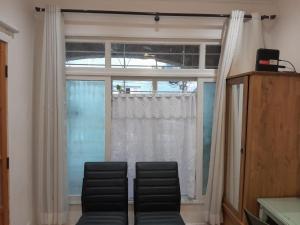 Cette chambre dispose d'une fenêtre avec deux chaises. dans l'établissement Studio em vila centenária em Copacabana, à Rio de Janeiro