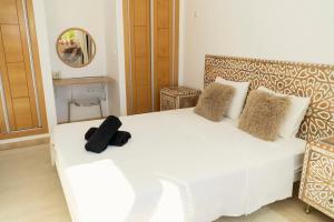 ein Schlafzimmer mit einem weißen Bett mit einem schwarzen Hut darauf in der Unterkunft Casita Amor- Monaco 9- Hacienda del Alamo in Corverica