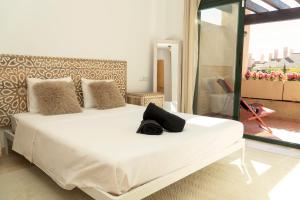 ein weißes Bett mit einem schwarzen Hut darüber in der Unterkunft Casita Amor- Monaco 9- Hacienda del Alamo in Corverica