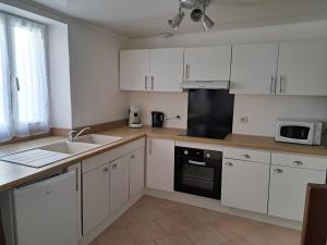 a kitchen with white cabinets and a sink and a microwave at Maison confortable sur RN6 in Armeau