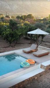 ein Swimmingpool mit Sonnenschirm und zwei Liegestühlen in der Unterkunft Villa Sunrise by the Sea in Kiotari