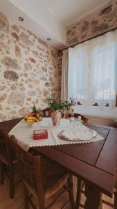 una sala da pranzo con tavolo in legno e parete in pietra di Nivritos Stoney Guesthouse a Nívritos