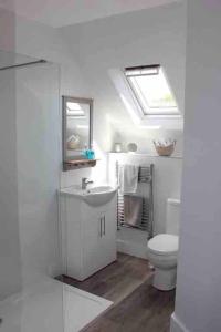 a white bathroom with a toilet and a sink at April Cottage in Lymington +39 photos