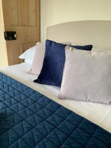 a bed with blue and white sheets and pillows at April Cottage in Lymington