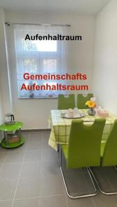 a table with green chairs and a sign on the wall at Kim Homestay A Zimmer 2 in Sömmerda