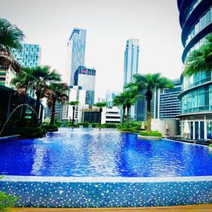 a large swimming pool with palm trees in a city at Vortex suites by DMK in Kuala Lumpur