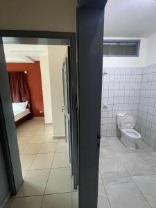a bathroom with a toilet and a door open at Les Résidences Céline Hôtel in Cotonou +3 photos
